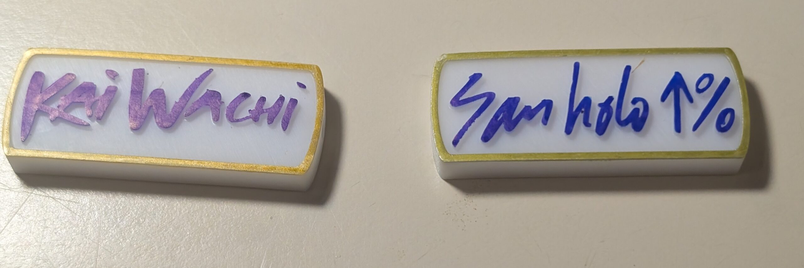Kai Wachi and San Holo charms with rounded edges and gold-colored borders
