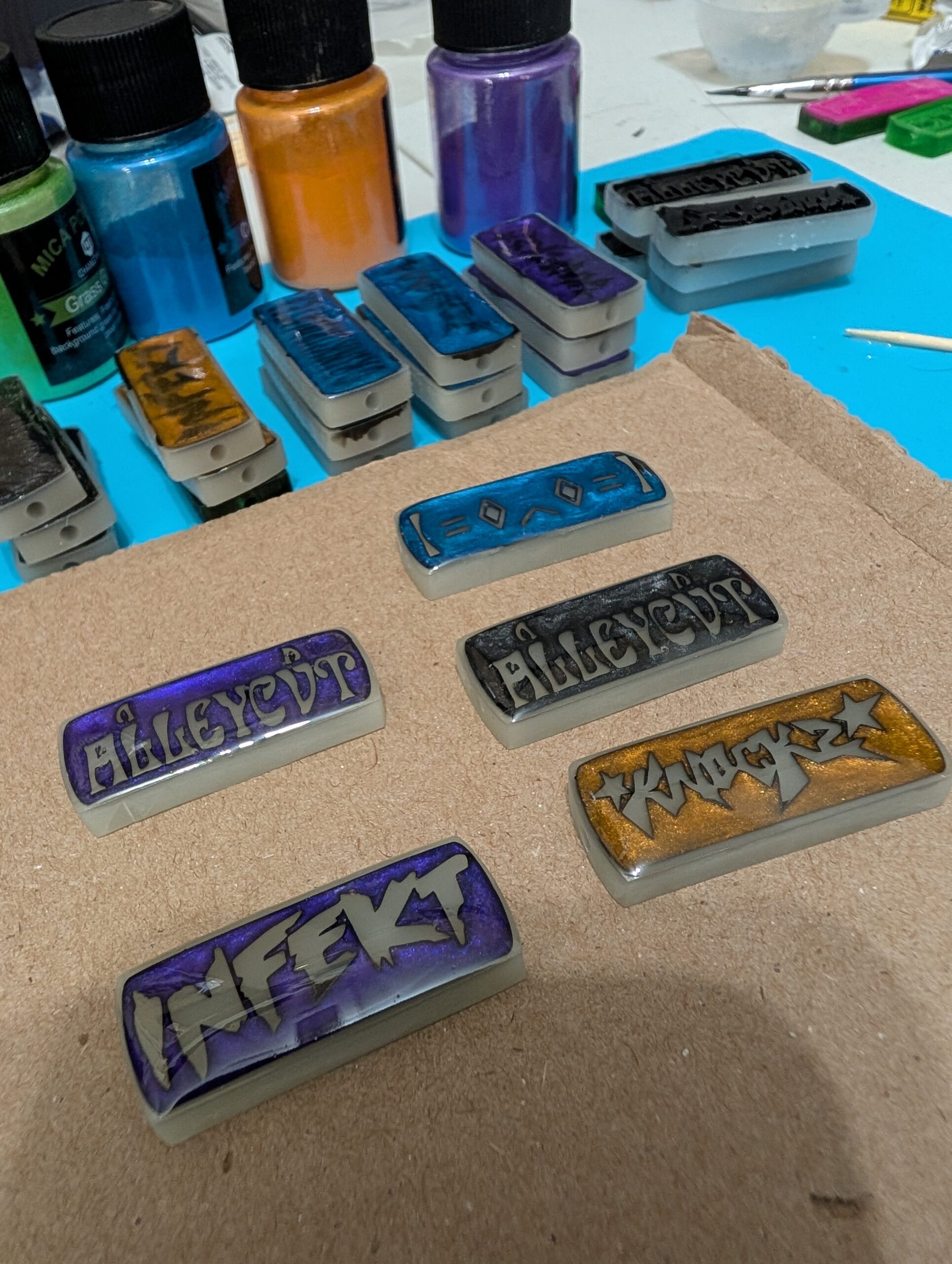 Metallic charms on a workbench alongside pigment jars